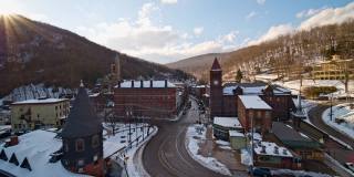 吉姆·索普的鸟瞰图，在宾夕法尼亚州阿巴拉契亚山脉的小树林里的美国小镇，在一场冬季风暴后被雪覆盖。飞机沿着主要街道穿过整个城市。