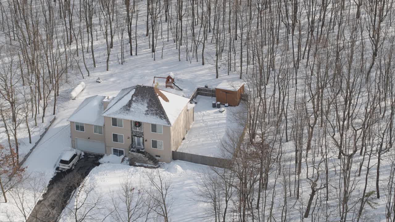 在一场冬季暴风雪后被雪覆盖的乡村社区的住宅。一辆车停在刚清理过的车道上。空中无人机视频。