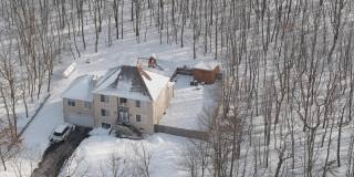 在一场冬季暴风雪后被雪覆盖的乡村社区的住宅。一辆车停在刚清理过的车道上。空中无人机视频。