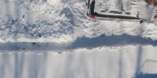 一名成年男子在一场冬季降雪后用铲子清理车道上的积雪。鸟瞰无人机正上方的慢动作视频。