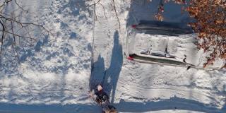 一名成年男子在一场冬季降雪后用除雪机清理车道上的积雪。鸟瞰图正上方无人机视频。