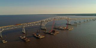 波托马克河重建鸟瞰图，靠近哈里·尼斯州长纪念馆/参议员托马斯·“麦克”·米德尔顿桥，连接弗吉尼亚州和马里兰州，水上有多艘浮吊船和建筑工地。