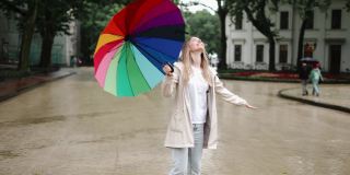 快乐的女人在城市里摘下雨伞享受雨