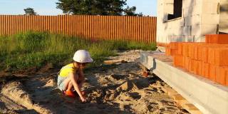 一个小女孩正在小屋的建筑工地上玩建筑工人的游戏。孩子安全，大人玩，梦想你的家，等待搬家。在游戏中训练，选择职业