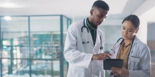两名年轻医生站在医院里一起看平板电脑的4k视频片段