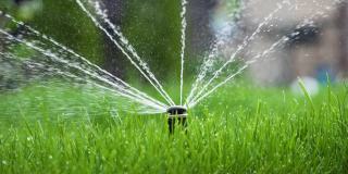 花园的草浇水。智能花园激活全自动喷灌系统工作在绿地公园，浇灌草坪，花木与头部旋转