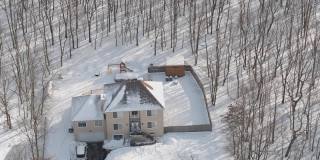 在一场冬季暴风雪后被雪覆盖的乡村社区的住宅。一辆车停在刚清理过的车道上。空中无人机视频。