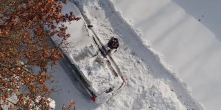 一个成年人在一场暴风雪后清理他的车。鸟瞰图正上方无人机视频。