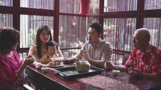 中国父亲与儿子在多代同堂期间享受传统的中秋节月饼和中国茶在家里下午茶聚会视频素材模板下载