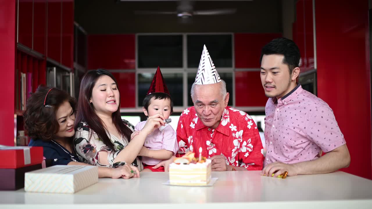 中国多代家庭在家里为爷爷孙子吹生日蜡烛庆祝生日