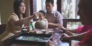 中国女儿在多代同堂期间喝茶，享用传统的中秋节月饼和下午茶聚会期间在家喝茶