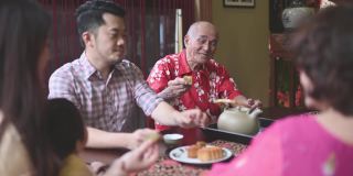 中国儿子在多代同堂期间喝茶，享用传统的中秋节月饼和下午茶聚会期间在家喝茶