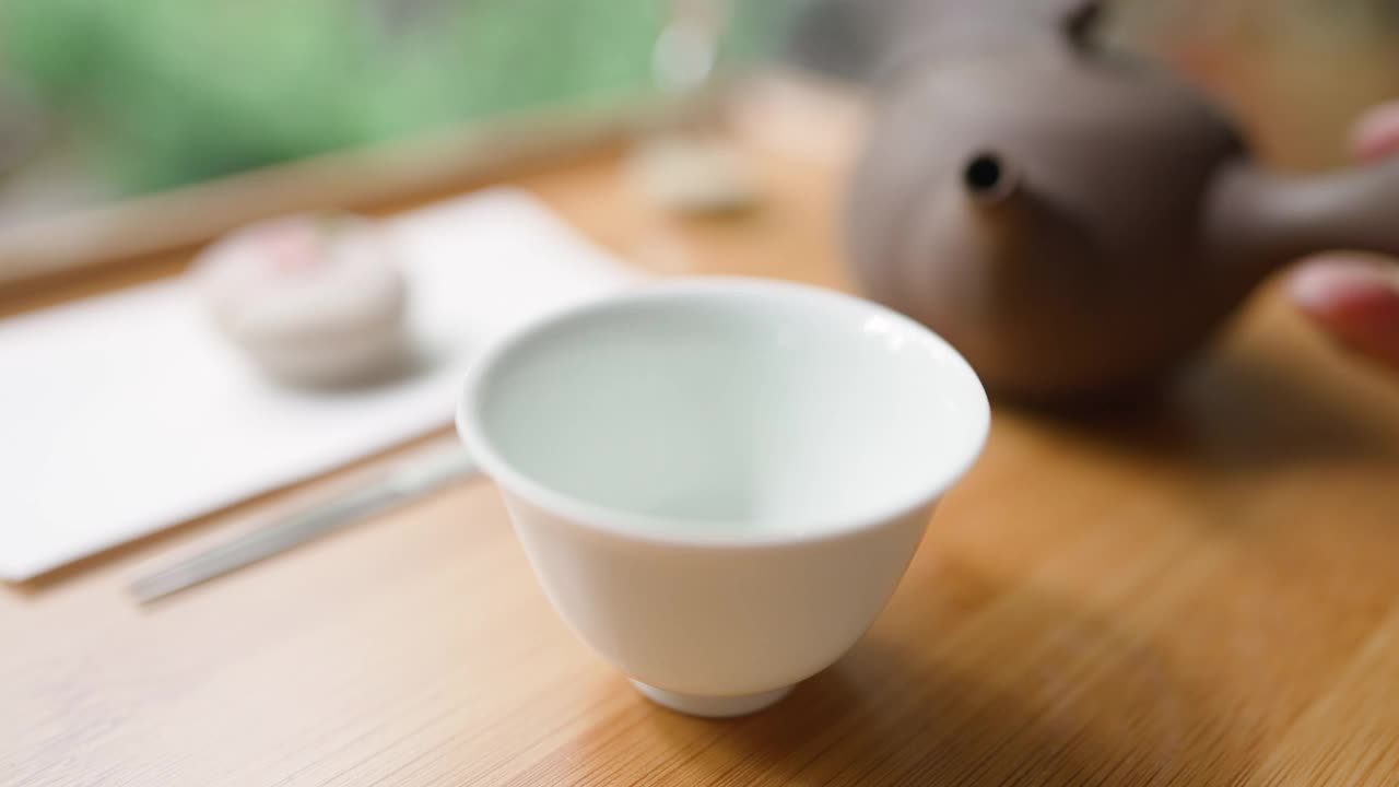 女用手将日本绿茶从罐中倒出。