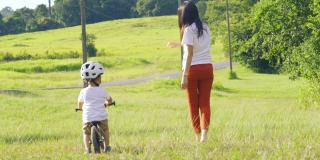 一位年轻的母亲在自然公园教儿子骑自行车。