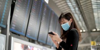 一名亚洲妇女戴口罩，以保护冠状病毒，并站在飞机上检查航班