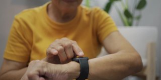 亚洲老年女性在家中使用智能手表测量锻炼后的心率。