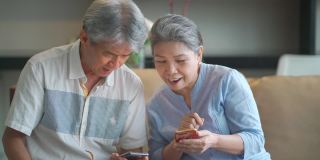 快乐的亚洲华人祖父母使用电话，在客厅愉快地交谈
