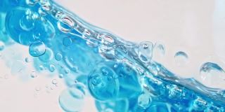 蓝色波浪水与泡沫在白色的背景。清澈的蓝色水中的氧气泡泡。矿泉水。富含氧气的水。缓慢的运动。微距镜头