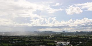 时光流逝，山景的背景是蓝色的天空和燃烧垃圾产生的烟雾。雨落在左边。