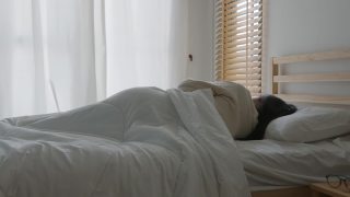 亚洲妇女睡在床上，早上醒来时伸展她的手臂视频素材模板下载