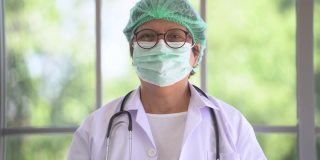 肖像的亚洲女医生脱下脸痕和微笑与幸福的生活。医疗保健产业的工人生活。老年人站在室内，以自然、树木和阳光为背景。