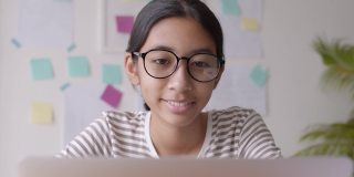亚洲妇女戴着眼镜在家里使用笔记本电脑早上