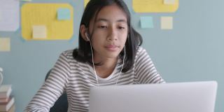 亚洲女孩在线学习与导师通过互联网上的笔记本电脑与耳机