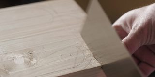 木匠用手锯从一块松木板上锯下一块木头。手工木工工具在工作。木工艺术
