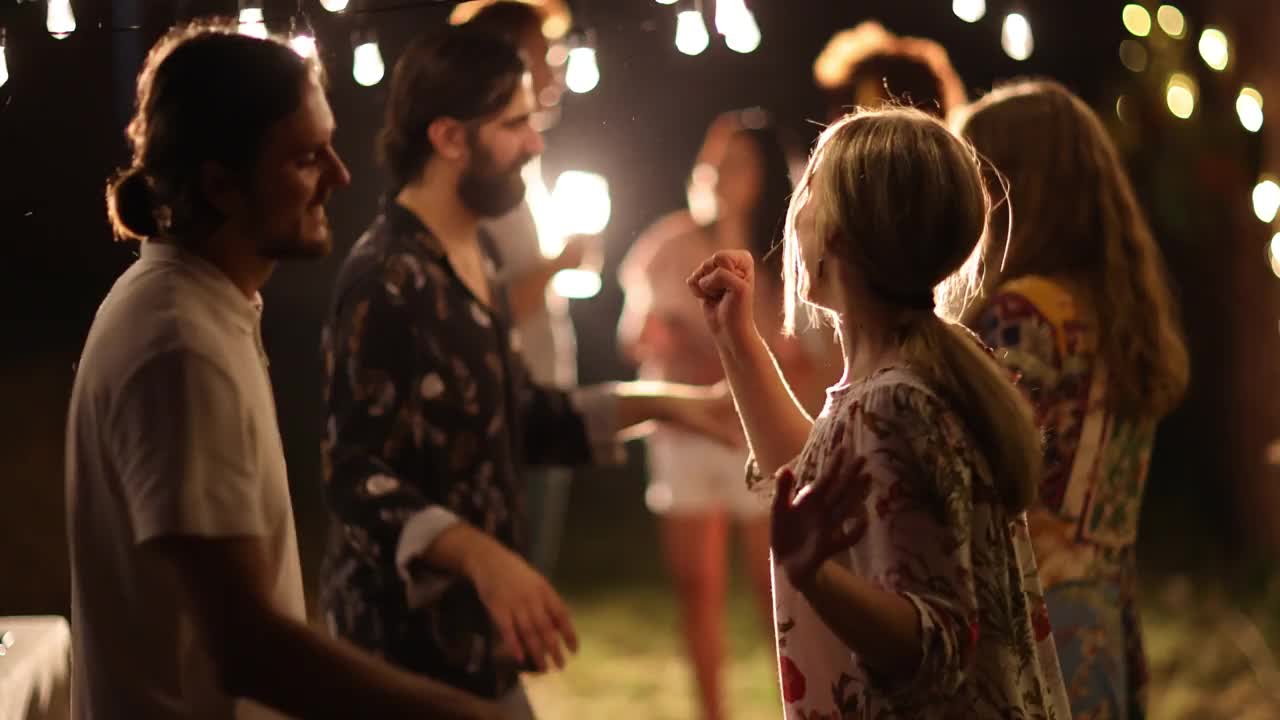 一对年轻夫妇在后院和朋友聚会时跳舞