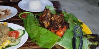 美味的印尼海鲜蟹菜，用香料和调味汁包在芭蕉叶盘里，与印尼餐厅的其他背景菜一起烹制
