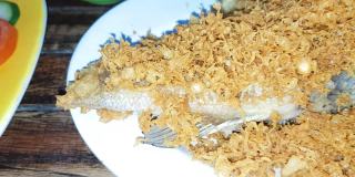 美味的印尼海鲜炒黑鲷鱼与油炸调味面糊，香料，浅盘与其他背景菜在印尼餐厅