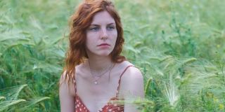 日落时草地上迷人的女性肖像。一个美丽的年轻女子走在麦田里。慢动作