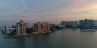 从空中俯瞰萨拉索塔市中心和金门点天际线上的豪华公寓，俯瞰在日出时挤满了游艇和船只的码头。