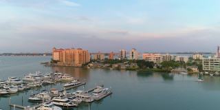从空中俯瞰萨拉索塔市中心和金门角天际线上的豪华公寓，日落前的清晨，码头上挤满了游艇和船只。