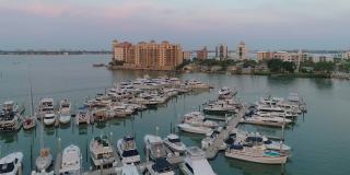 从空中俯瞰萨拉索塔市中心和金门角天际线上的豪华公寓，日落前的清晨，码头上挤满了游艇和船只。