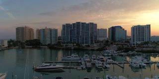 从空中俯瞰萨拉索塔市中心和金门点天际线上的豪华公寓，俯瞰在日出时挤满了游艇和船只的码头。