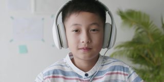 肖像亚洲男孩早上戴着耳机在家快乐的微笑