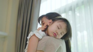 亚洲美丽慈爱的母亲抱着熟睡的女婴在她的臂弯温柔。父母微笑着站在小宝贝小女儿的肩膀上休息。家庭亲子关系概念。视频素材模板下载