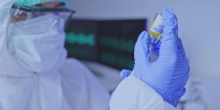 个人防护装备的科研人员和医生团队在洁净工厂的实验室研制新型冠状病毒疫苗。药物生物学和药物制造研究。