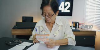 亚洲资深女性每月计算开支支票收据支付。