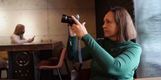 女人用相机拍视频。餐厅的现代观点。深绿色的裙子。手持数字设备的人