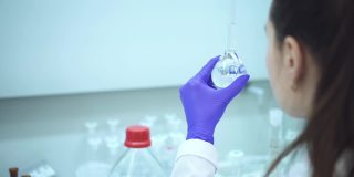 女科学家在化学实验室拿着瓶盖瓶和吸管。化学透明
