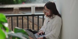 十几岁的妇女在家里的阳台上使用电脑