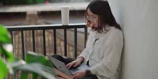 十几岁的妇女在家里的阳台上使用电脑