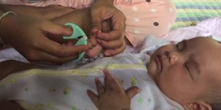 妈妈正在给她的孩子剪指甲
