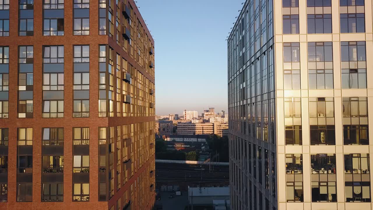 日落时分，镜头在两座办公大楼之间穿梭。阳光反射在窗户上