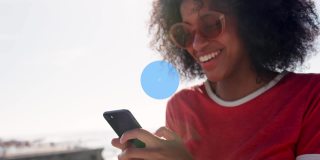 网络数字偶像对抗在海滩上使用智能手机的非裔美国女性