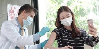 一名亚洲妇女在医生接种疫苗时自拍。