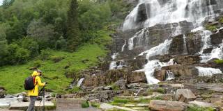 沃斯、Hordaland、挪威。春天的瀑布。年轻的白人女性游客正在拍摄挪威最高的瀑布。著名的挪威地标和受欢迎的目的地