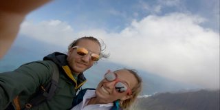 一对年轻夫妇在夏威夷考艾岛远足，从山顶俯瞰太平洋自拍。爱冒险的夫妇徒步旅行和自拍视频